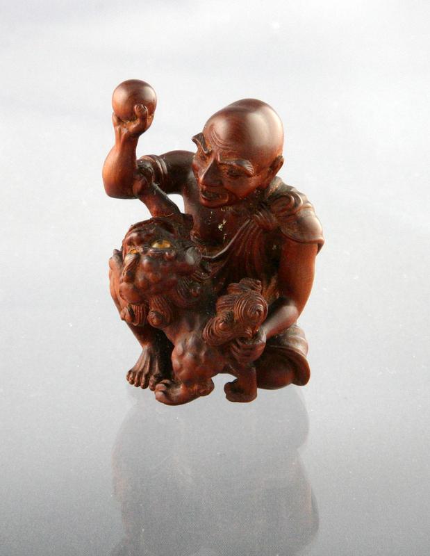 Netsuke of a Rakan Playing with a Chinese Lion