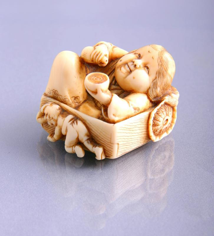 Netsuke: Ivory Figure of Okame in Basket with Sake